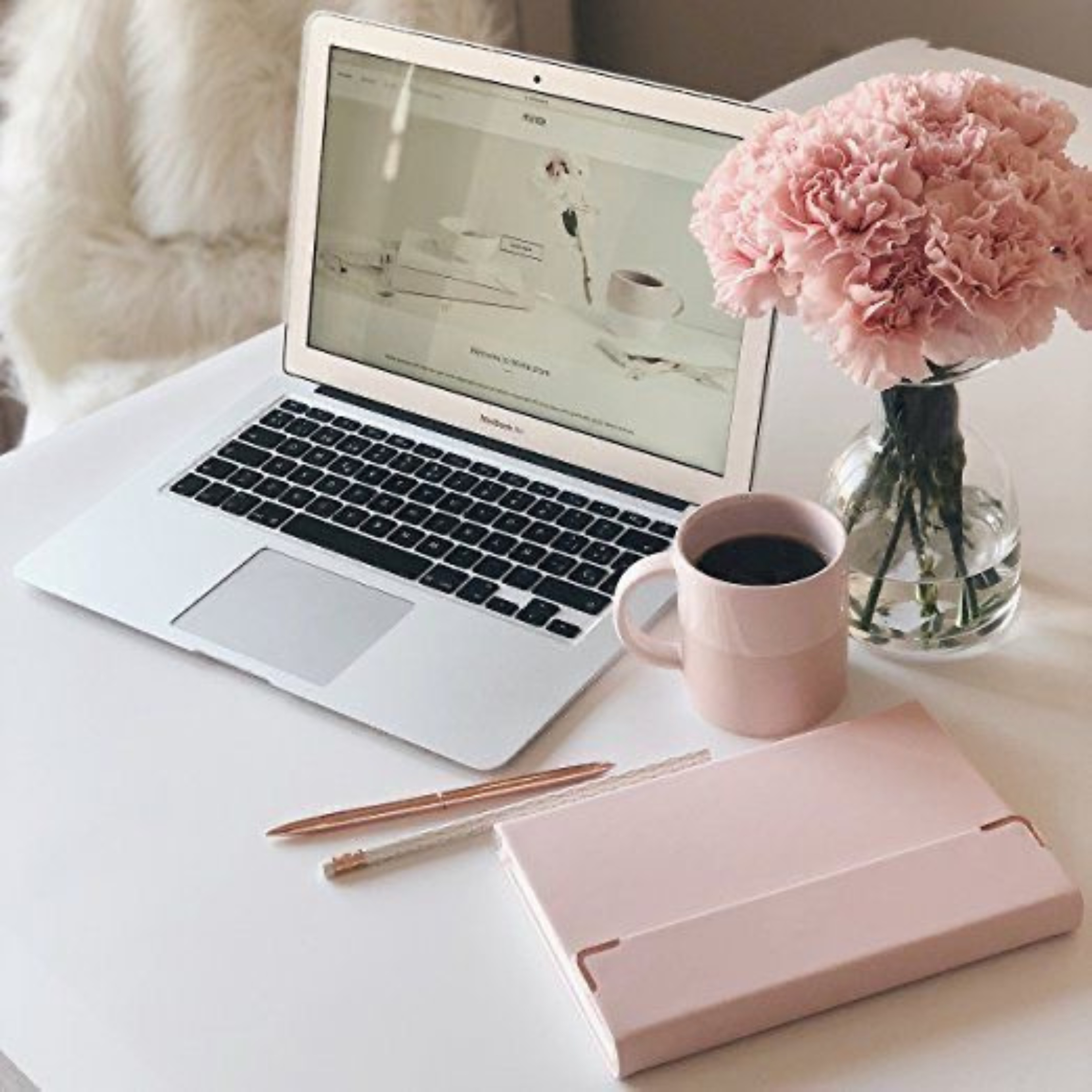 Laptop on desk with flowers and journal